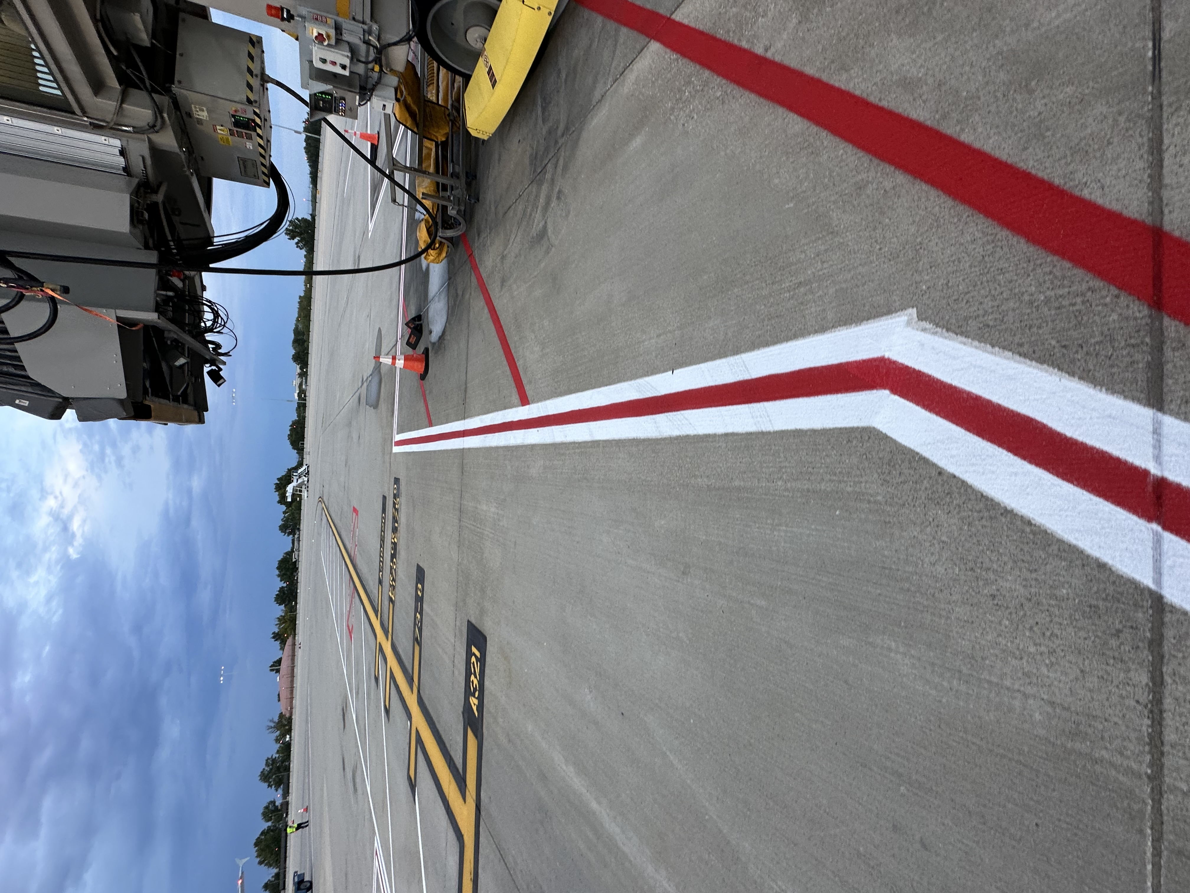 Fresh red, white and yellow aircraft gate markings beside a jet bridge